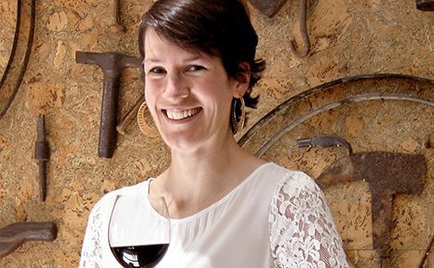 Female teacher in a cellar shows her class a glass of red wine while they make notes